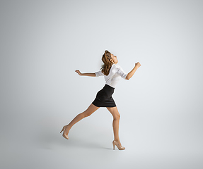 Image showing Caucasian woman in office clothes running isolated on grey studio background