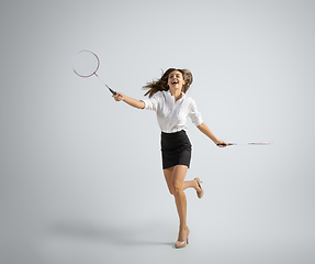 Image showing Caucasian woman in office clothes plays badminton isolated on grey studio background