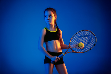 Image showing Little caucasian girl playing tennis isolated on blue background in neon light