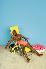 Image showing Happy young man resting on blue studio background