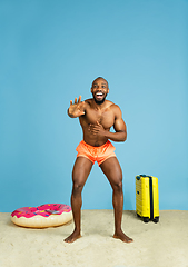 Image showing Happy young man resting on blue studio background