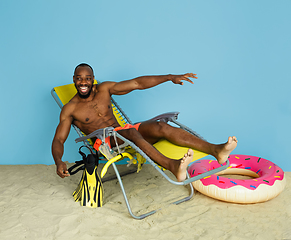 Image showing Happy young man resting on blue studio background