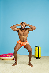 Image showing Happy young man resting on blue studio background