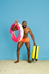 Image showing Happy young man resting on blue studio background