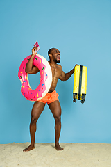 Image showing Happy young man resting on blue studio background