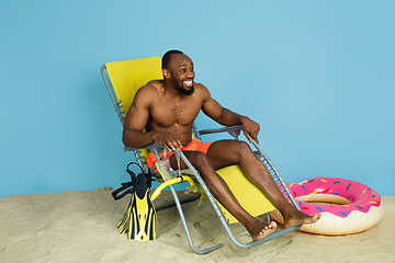 Image showing Happy young man resting on blue studio background