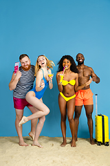 Image showing Happy young friends resting on blue studio background