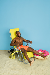 Image showing Happy young man resting on blue studio background