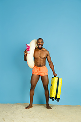 Image showing Happy young man resting on blue studio background