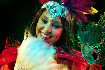 Image showing Beautiful young woman in carnival mask and masquerade costume in colorful lights