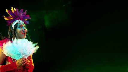 Image showing Beautiful young woman in carnival mask and masquerade costume in colorful lights, flyer