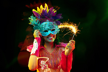 Image showing Beautiful young woman in carnival mask and masquerade costume in colorful lights