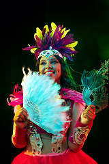 Image showing Beautiful young woman in carnival mask and masquerade costume in colorful lights