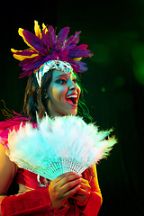 Image showing Beautiful young woman in carnival mask and masquerade costume in colorful lights