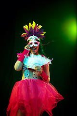 Image showing Beautiful young woman in carnival mask and masquerade costume in colorful lights