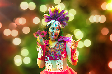 Image showing Beautiful young woman in carnival mask and masquerade costume in colorful lights