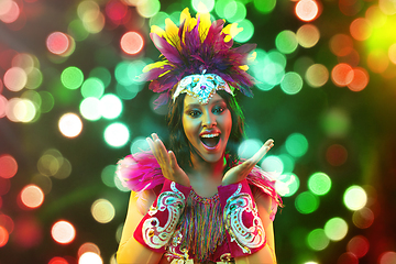 Image showing Beautiful young woman in carnival mask and masquerade costume in colorful lights