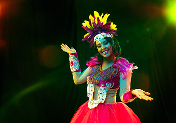 Image showing Beautiful young woman in carnival mask and masquerade costume in colorful lights