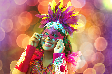 Image showing Beautiful young woman in carnival mask and masquerade costume in colorful lights