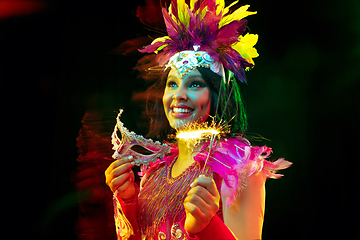 Image showing Beautiful young woman in carnival mask and masquerade costume in colorful lights