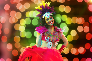 Image showing Beautiful young woman in carnival mask and masquerade costume in colorful lights