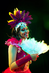 Image showing Beautiful young woman in carnival mask and masquerade costume in colorful lights