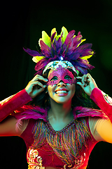 Image showing Beautiful young woman in carnival mask and masquerade costume in colorful lights