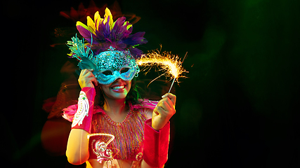 Image showing Beautiful young woman in carnival mask and masquerade costume in colorful lights, flyer