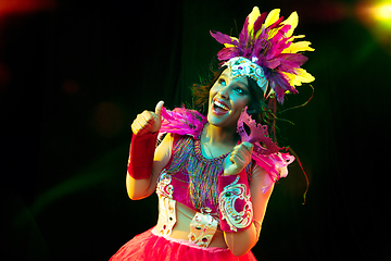 Image showing Beautiful young woman in carnival mask and masquerade costume in colorful lights