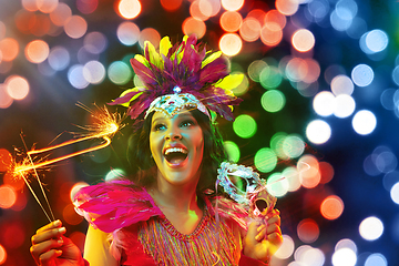 Image showing Beautiful young woman in carnival mask and masquerade costume in colorful lights