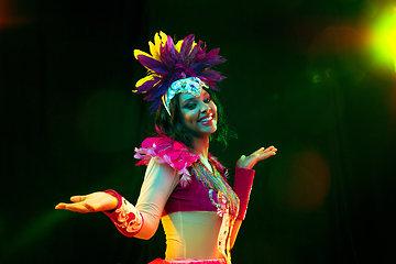 Image showing Beautiful young woman in carnival mask and masquerade costume in colorful lights