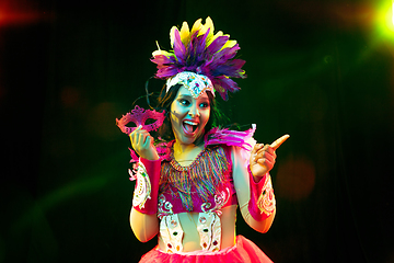 Image showing Beautiful young woman in carnival mask and masquerade costume in colorful lights