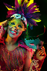 Image showing Beautiful young woman in carnival mask and masquerade costume in colorful lights