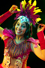 Image showing Beautiful young woman in carnival mask and masquerade costume in colorful lights