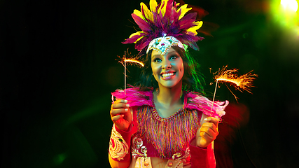 Image showing Beautiful young woman in carnival mask and masquerade costume in colorful lights, flyer