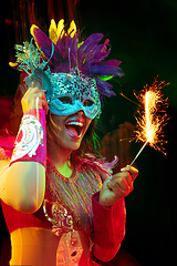 Image showing Beautiful young woman in carnival mask and masquerade costume in colorful lights