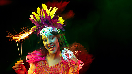 Image showing Beautiful young woman in carnival mask and masquerade costume in colorful lights