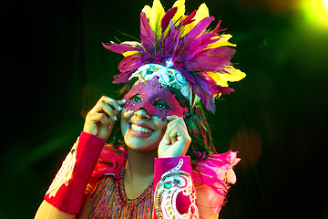 Image showing Beautiful young woman in carnival mask and masquerade costume in colorful lights