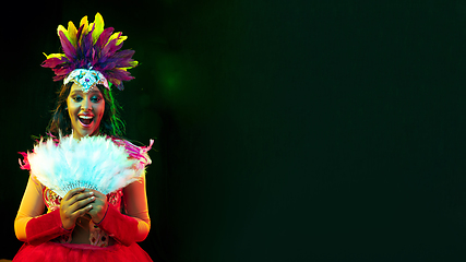 Image showing Beautiful young woman in carnival mask and masquerade costume in colorful lights, flyer