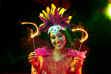 Image showing Beautiful young woman in carnival mask and masquerade costume in colorful lights