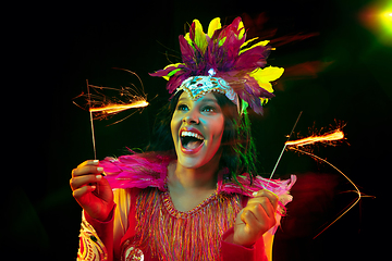 Image showing Beautiful young woman in carnival mask and masquerade costume in colorful lights