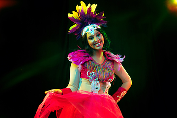 Image showing Beautiful young woman in carnival mask and masquerade costume in colorful lights