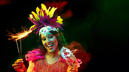 Image showing Beautiful young woman in carnival mask and masquerade costume in colorful lights, flyer