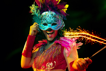 Image showing Beautiful young woman in carnival mask and masquerade costume in colorful lights