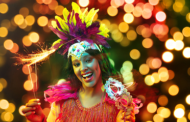 Image showing Beautiful young woman in carnival mask and masquerade costume in colorful lights