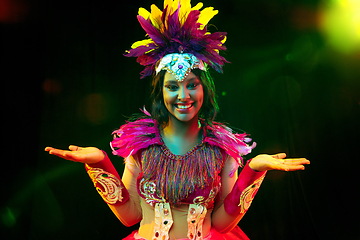 Image showing Beautiful young woman in carnival mask and masquerade costume in colorful lights