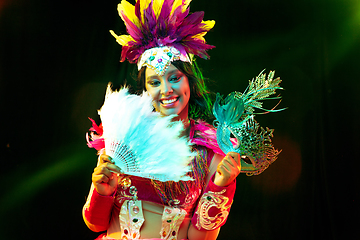 Image showing Beautiful young woman in carnival mask and masquerade costume in colorful lights