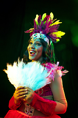 Image showing Beautiful young woman in carnival mask and masquerade costume in colorful lights