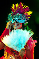 Image showing Beautiful young woman in carnival mask and masquerade costume in colorful lights