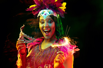 Image showing Beautiful young woman in carnival mask and masquerade costume in colorful lights